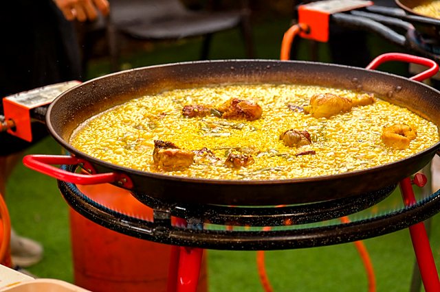 Paella rice simmering on a gas paella burner with red legs